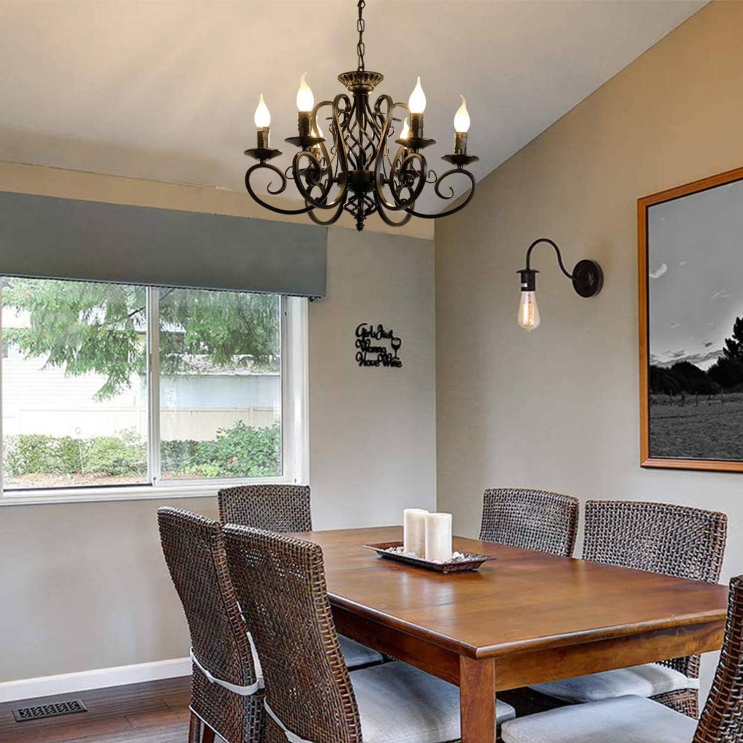 A six-light iron chandelier over a dining table, with a wall light beside the window